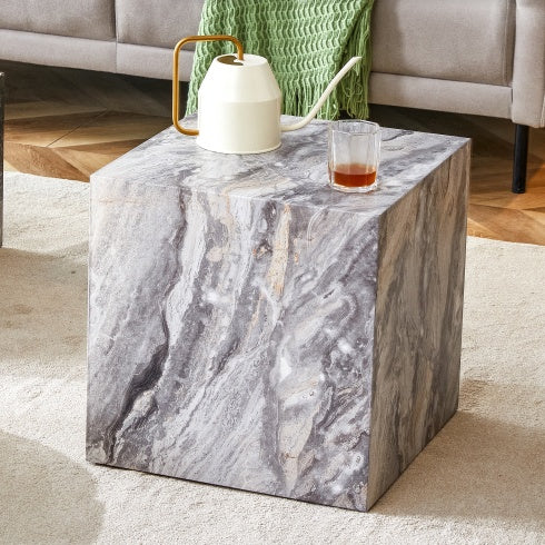 Marble-patterned side table with a glass of juice and a white pitcher in a living room setting.